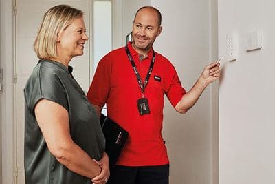 Montør fra Sector Alarm viser en kunde alarmsystemet i gangen